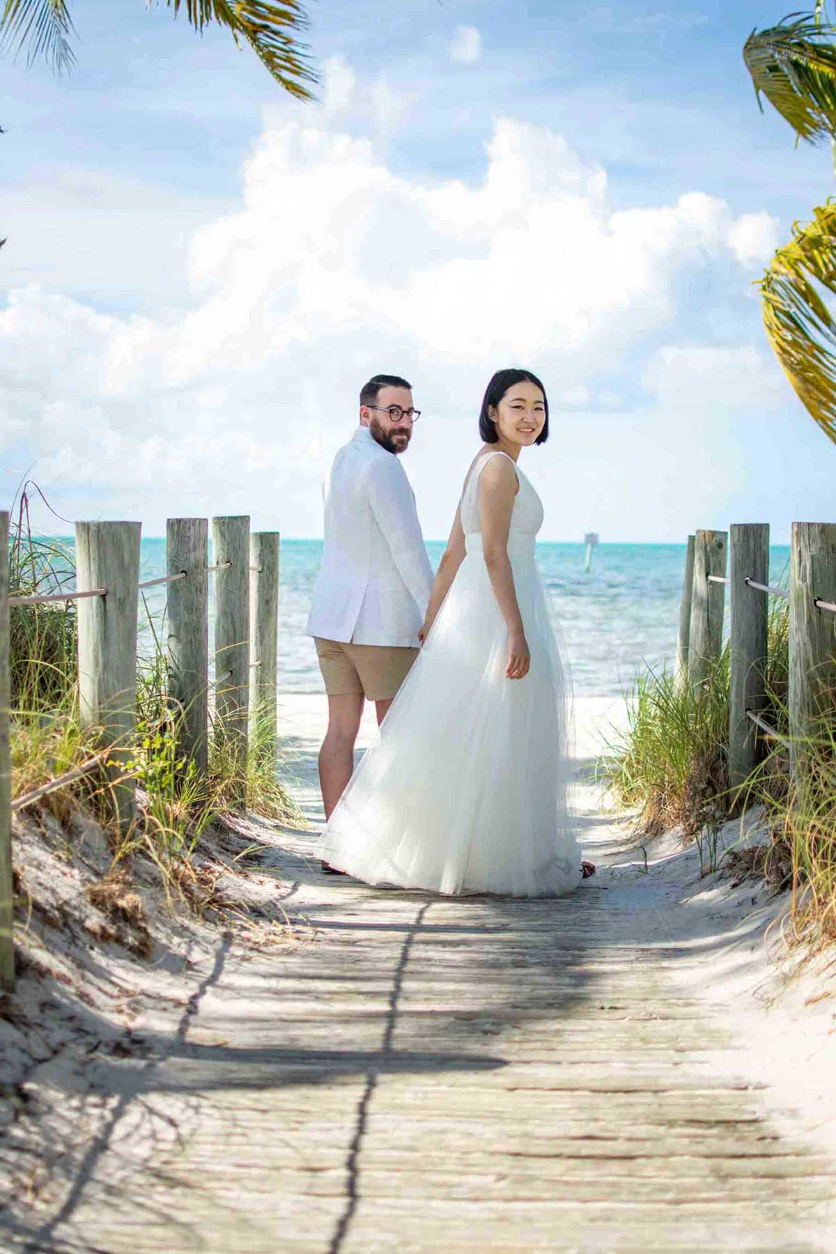 a bride and groom on a boardwalk pathway at Smathers beach in Key West, FL