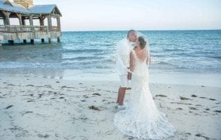 A bride and groom exchanging vows on the beach near a pier, captured beautifully by a skilled Key West wedding photographer.