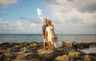 A couple standing on rocks in front of the ocean during their Key West wedding ceremony.