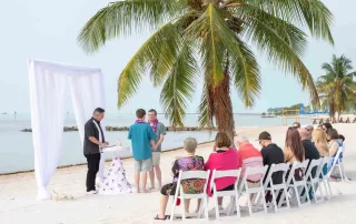 A picturesque beach wedding ceremony under the shade of palm trees, expertly coordinated by our experienced Key West wedding planners.