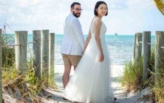 A bride and groom standing on a wooden walkway during their beach wedding in Key West.