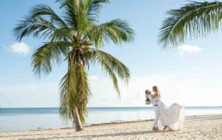 A bride and groom exchanging vows on a picturesque beach surrounded by palm trees