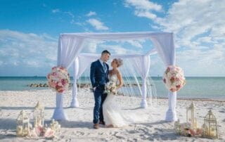 A stunning bride and groom exchanging vows under a picturesque beach arch, captured beautifully by a talented Key West wedding photographer.