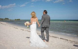 Capturing a beautiful moment, this key west wedding photographer documents a bride and groom as they walk hand in hand on the beach.