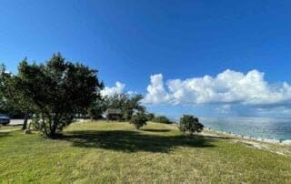 A picturesque grassy area with trees and a breathtaking view of the ocean, perfect for capturing stunning photographs on your special Key West wedding day.