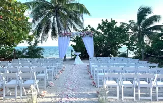 A picturesque beach wedding ceremony set up with white chairs and palm trees, captured beautifully by a talented Key West wedding photographer.