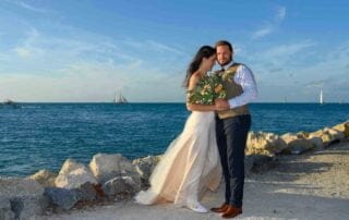 A key west bride and groom posing for a photo by the ocean.