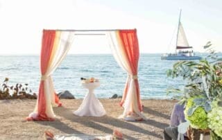 A picturesque beach wedding ceremony with a sailboat in the background, captured beautifully by a Key West wedding photographer.