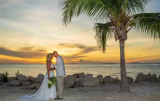 A bride and groom share a romantic kiss on the beach at sunset, captured beautifully by a talented Key West wedding photographer.