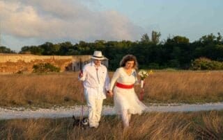 A couple walking through a field with their dog during their Key West wedding.