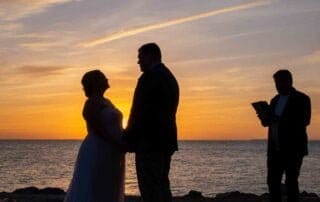 A stunning bride and groom standing in front of the ocean at sunset, captured beautifully by a talented Key West wedding photographer.