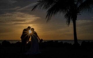 Silhouetted bride and groom exchange vows on the beach at sunset, captured by a talented Key West wedding photographer.