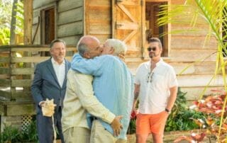 A group of men embracing affectionately in front of a house, captured beautifully by a talented key west wedding photographer.