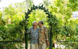 Two older men sharing a heartfelt kiss in a picturesque garden during their Key West wedding ceremony.