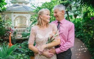 A key west wedding officiant and key west wedding photographer capture an older couple posing in front of a gazebo in a greenhouse as part of their key west wedding package.