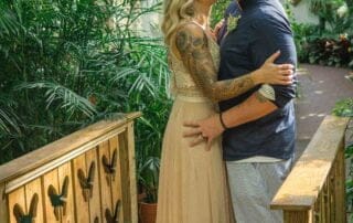 A couple kisses on a bridge amidst a lush greenhouse, made possible by a skilled Key West wedding planner.