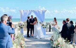 A couple is elegantly walking down the aisle at their beautiful beach wedding ceremony in Key West.