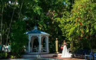 A bride standing in front of a gazebo next to a pool captured by a skillful key west wedding photographer.