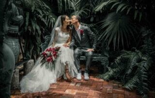 A bride and groom share a passionate kiss on a bench in a tropical garden, captured beautifully by a talented Key West wedding photographer.