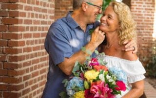 An older couple embracing in front of a brick archway during their Key West wedding ceremony.