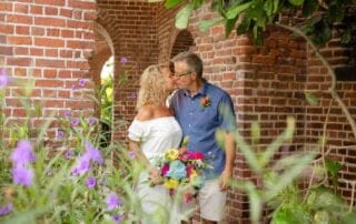 A bride and groom share a romantic kiss in front of a brick archway during their Key West wedding ceremony.