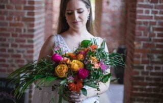 A bride holding a colorful bouquet in an archway at her Key West wedding.