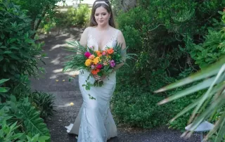 A beautiful bride strolling along a scenic pathway, holding her wedding bouquet.