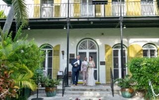A bride and groom standing on the steps of a house captured by a key west wedding photographer.