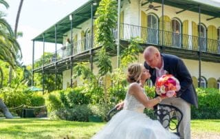 A bride and groom kissing in front of a house, captured beautifully by a talented Key West wedding photographer.