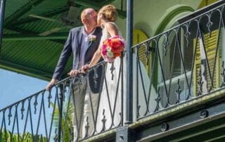 A bride and groom sharing a romantic kiss on the balcony of a house during their Key West wedding.