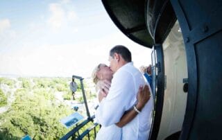 A bride and groom sharing a romantic kiss on the balcony of a lighthouse during their Key West wedding.