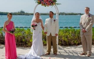 The bride and groom are having their picture taken by a key west wedding photographer on the sandy shoreline.