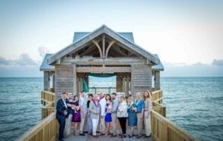 A group of people posing on a wooden pier during a Key West wedding.