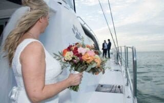 A bride and groom holding hands on the bow of a boat, captured beautifully by a key west wedding photographer.
