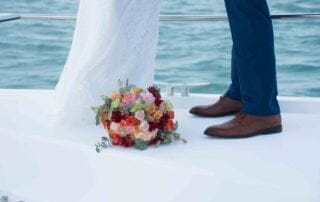 A bride and groom happily posing on the bow of a boat, captured beautifully by a skilled Key West wedding photographer.