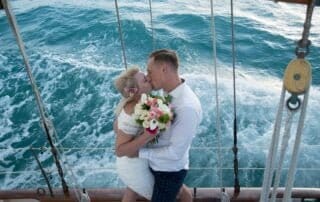 A bride and groom passionately kiss on the deck of a sailboat during their Key West wedding.