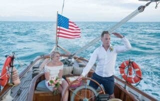 An enchanting key west wedding ceremony takes place on a boat, where a beaming bride and groom exchange vows against the backdrop of a fluttering American flag.