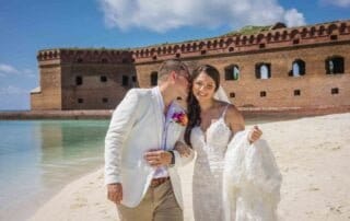 A bride and groom exchange vows on the beach in front of a Fort McDowell fort, captured beautifully by a Key West wedding photographer.