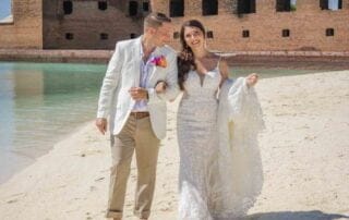 A bride and groom standing on the beach for their dream Key West wedding, with an old fort creating a picturesque backdrop.