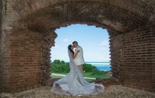 A bride and groom sharing a passionate kiss in an enchanting archway of a historic fort, captured beautifully by a talented Key West wedding photographer.