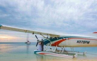 A small plane sits on the beach next to a boat, offering a picturesque setting for Key West wedding packages.