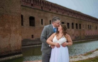 A bride and groom share a passionate kiss in front of an old fort captured by a talented Key West wedding photographer.