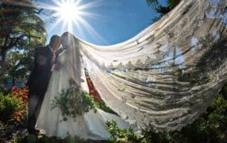 A bride and groom kiss under a veil in a romantic garden as captured by a talented Key West wedding photographer.