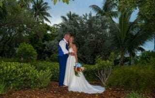 A bride and groom sharing a passionate kiss under the vibrant tropical foliage of a lush garden, captured beautifully by a skilled Key West wedding photographer.