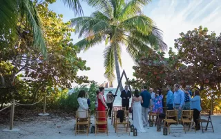 A picturesque beach wedding ceremony under a palm tree, enhanced by the expertise of key west wedding planners.