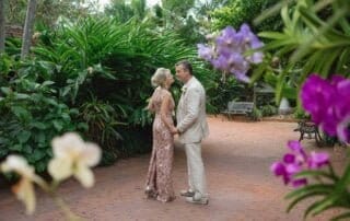 A bride and groom standing in a garden with orchids during their Key West wedding.