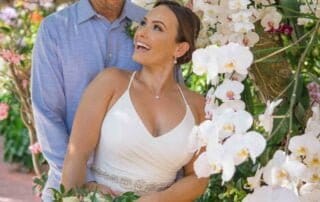 A bride and groom posing in front of orchids during their key west wedding.
