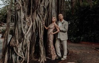 A bride and groom posing next to a picturesque banyan tree on their special day, captured beautifully by a professional Key West wedding photographer.