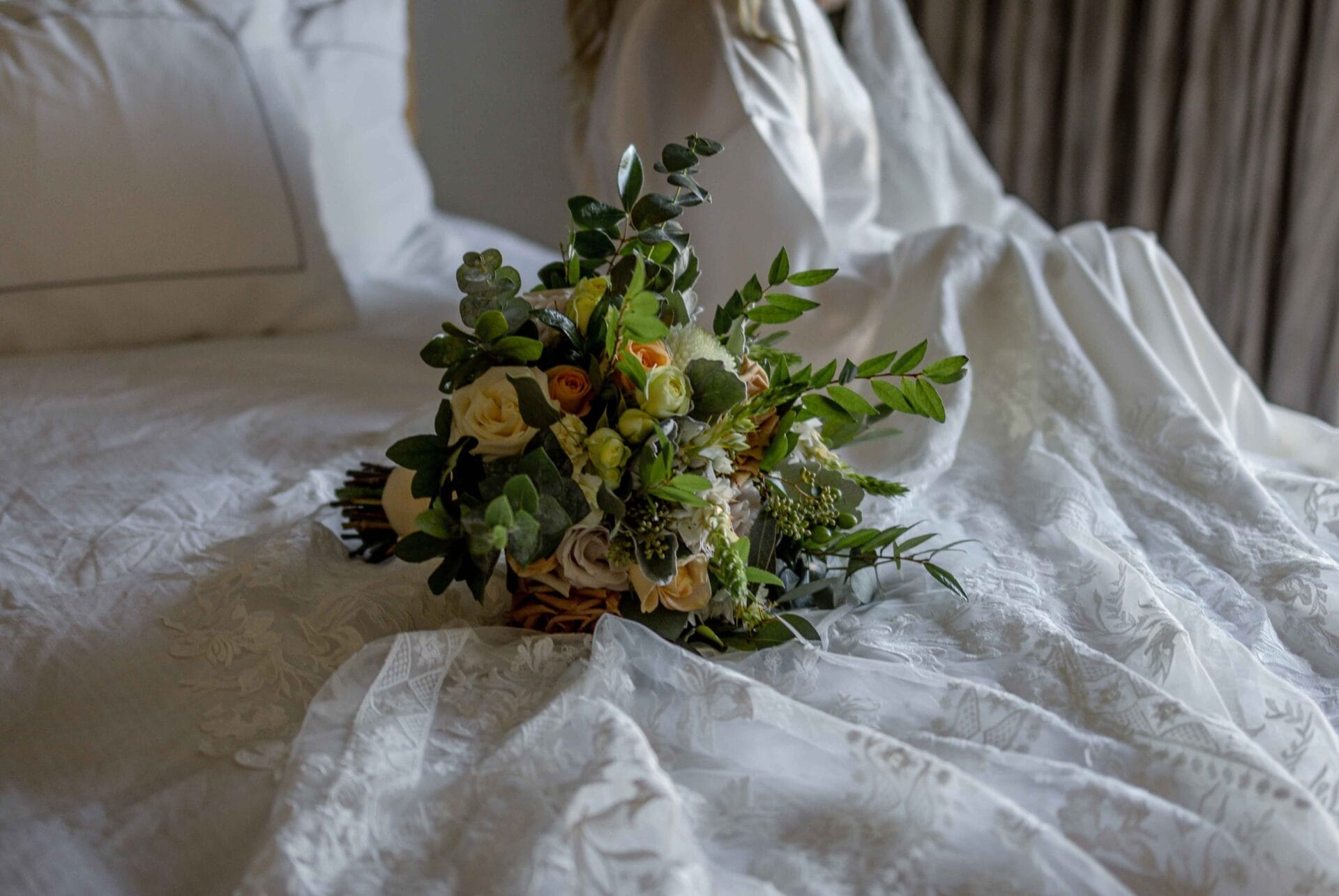 A bride sitting on a bed with a bouquet of flowers at a key west wedding.