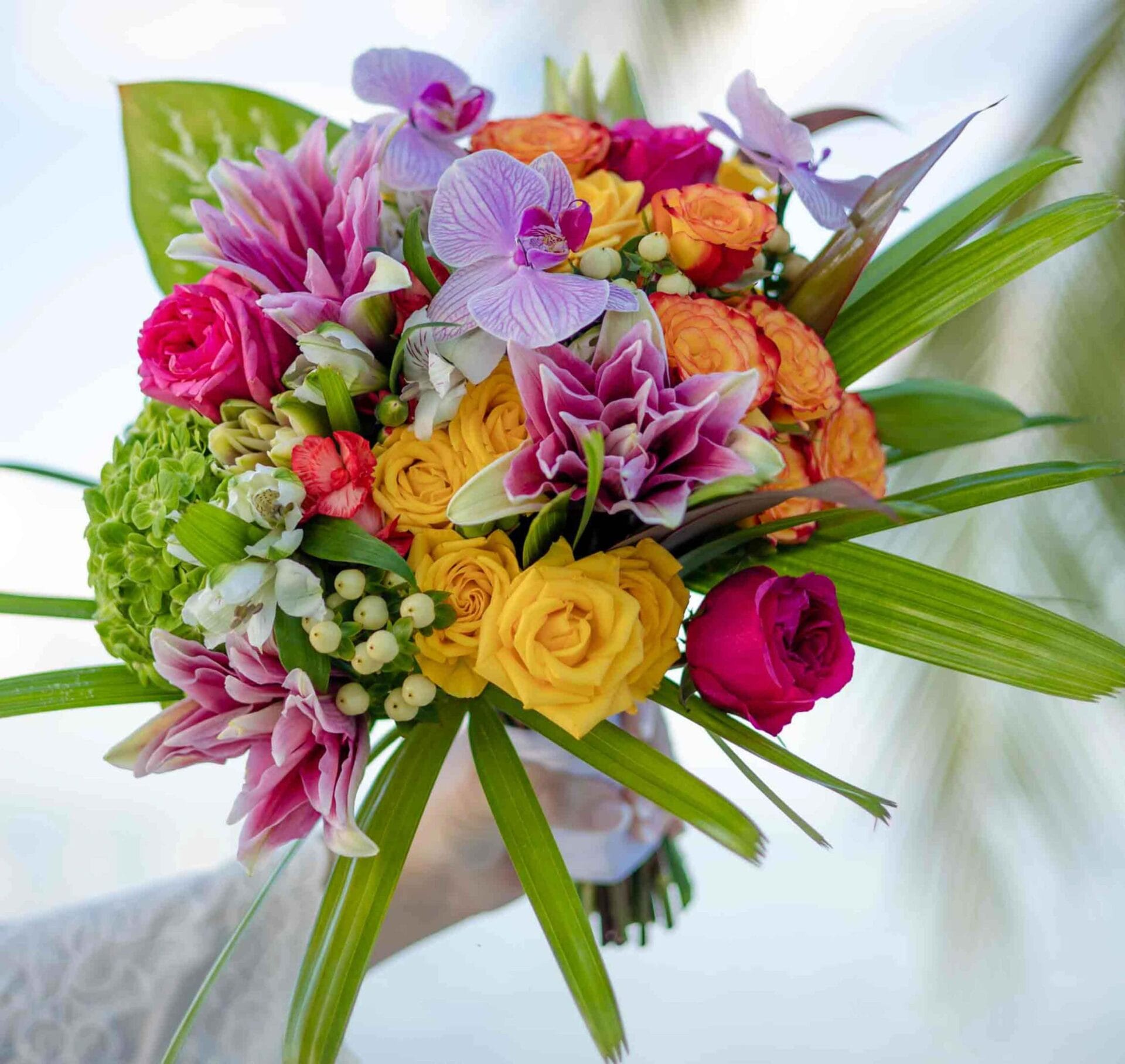 A woman is holding a bouquet of flowers for her beach wedding.
